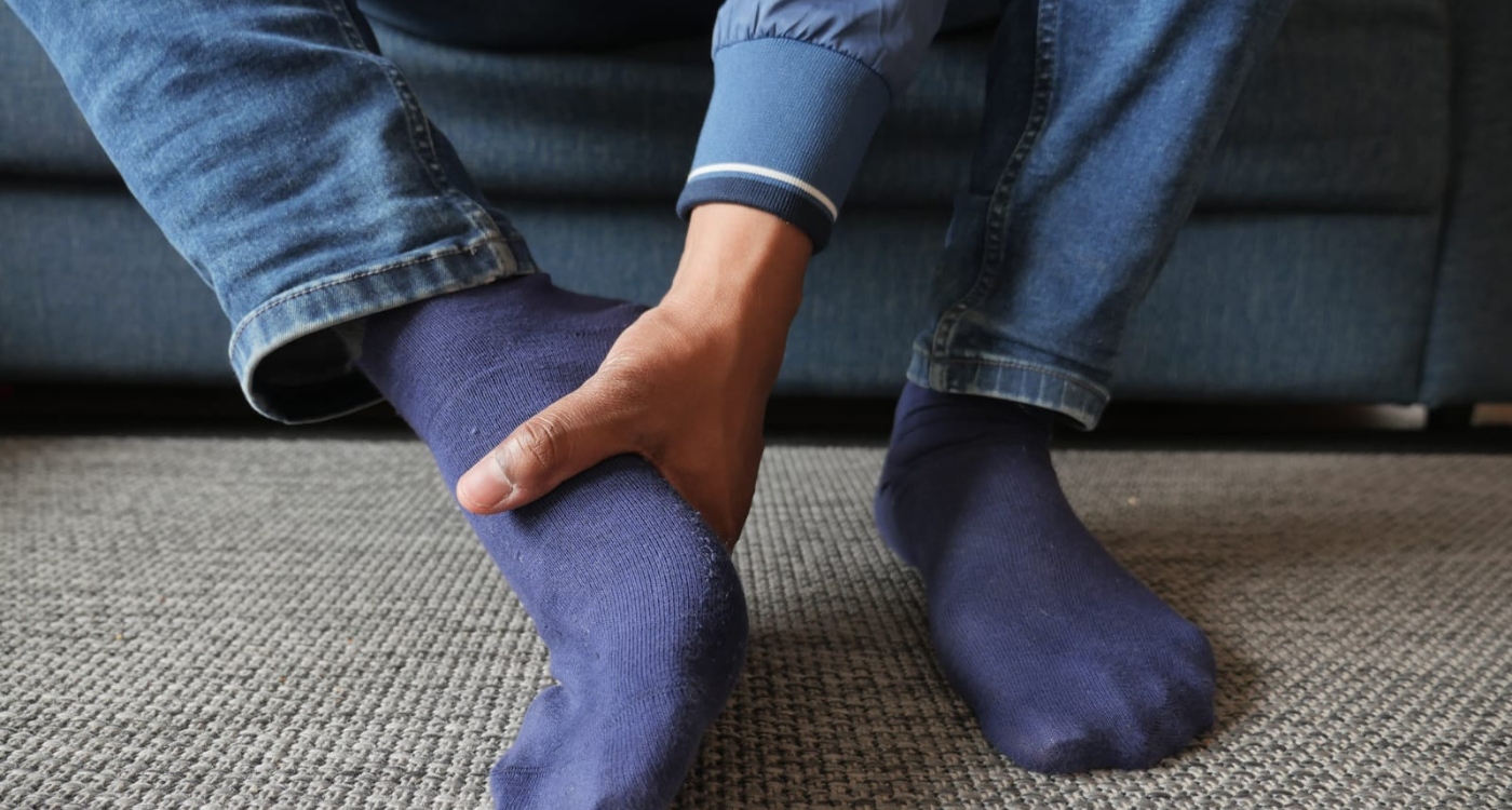 A man in blue socks has foot or ankle pain