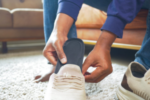 A man inserts custom orthotics into his shoes