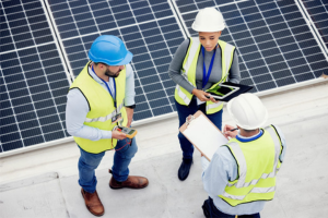 Workers discuss the solar panel fitting process on a roof