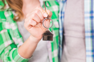 Couple holding key with a house shaped keyring after purchasing first house